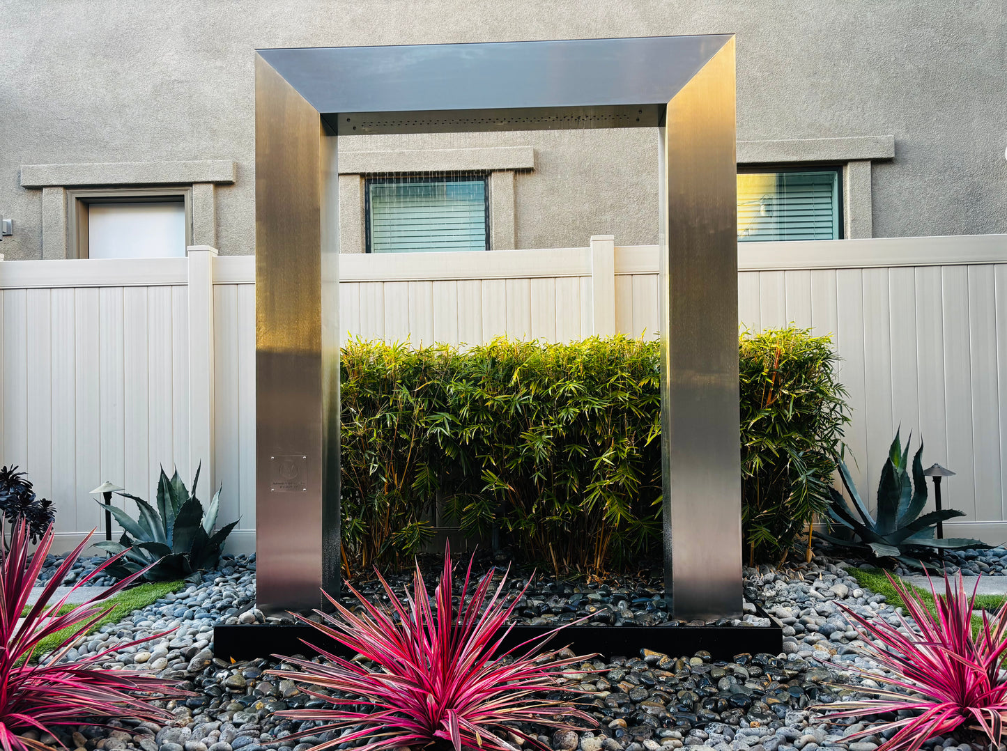 Customer-installed 304-grade stainless steel rain curtain fountain door with a polished metal frame and flowing water curtain in natural daylight, creating a high-end backyard water feature for luxury patio and landscape design