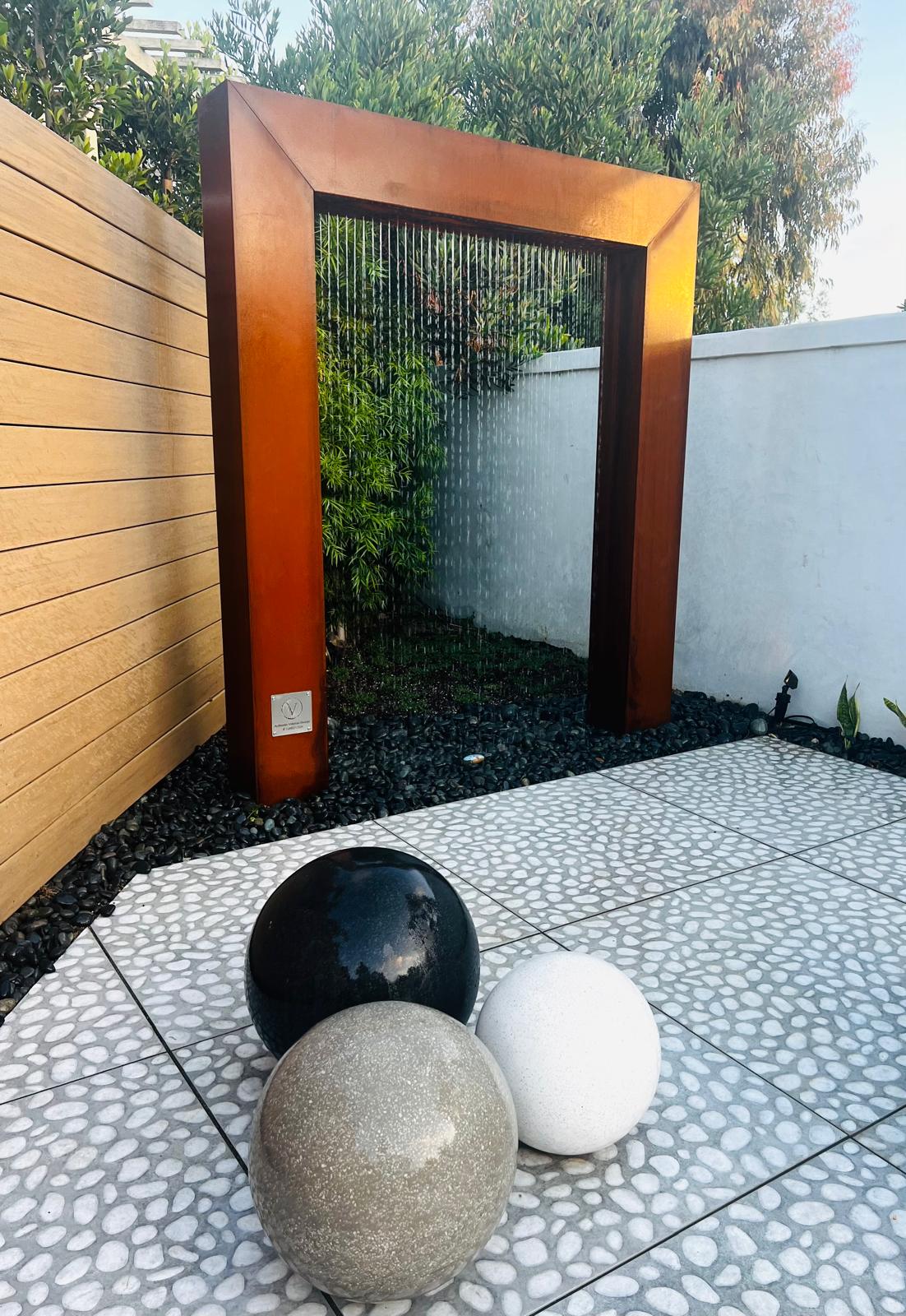 Corten steel rain curtain fountain with stone spheres